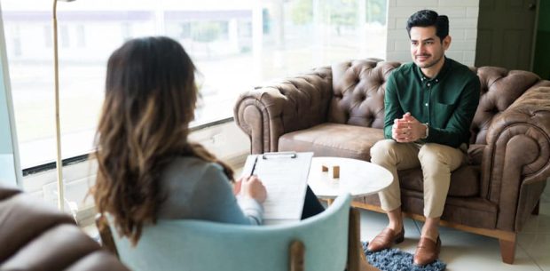 Businessman listening to female counselor during therapy session while sitting in office